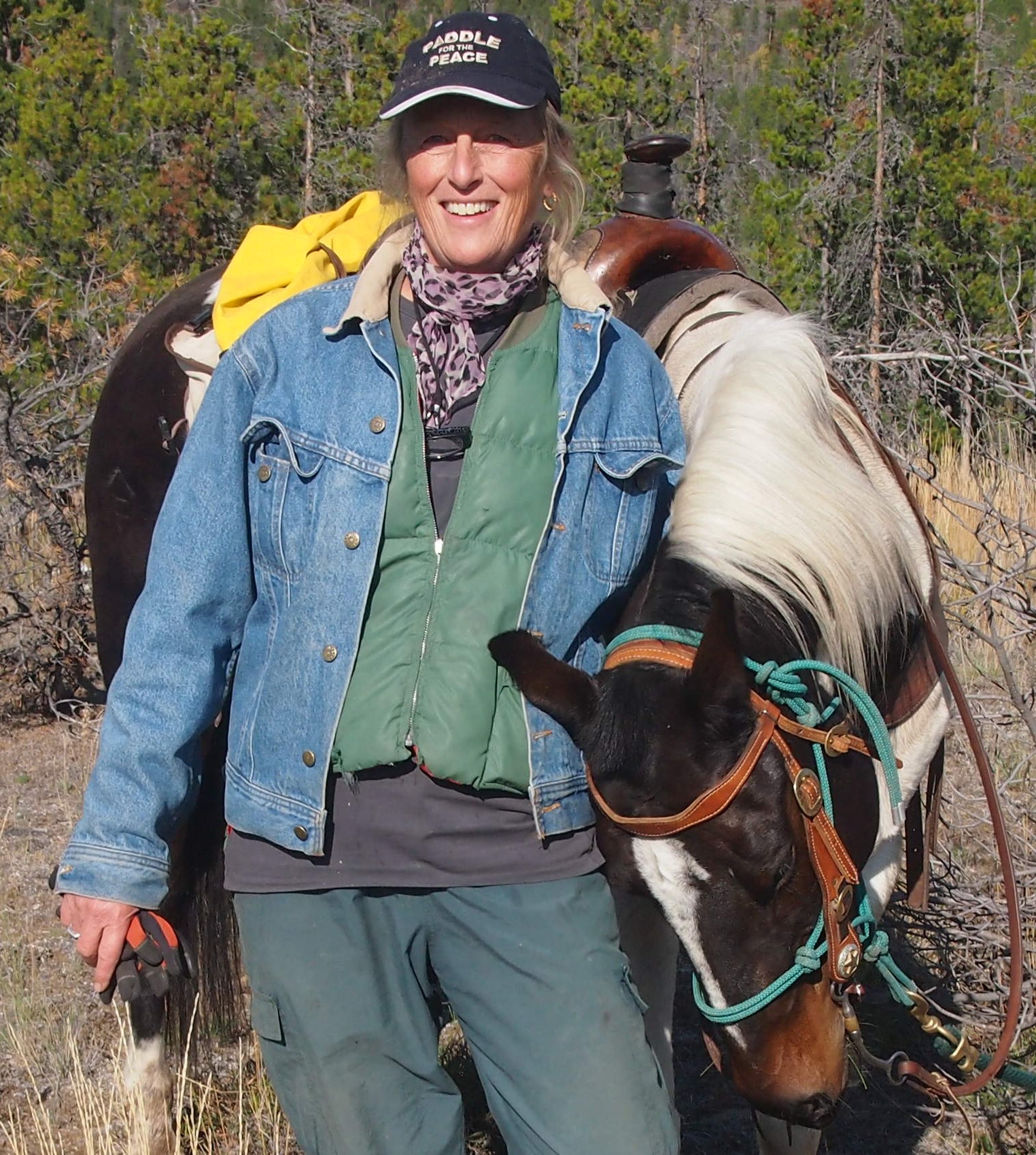 Eveline Wolterson smiles wearing a "Paddle for the Peace" baseball hat standing next to a horse.