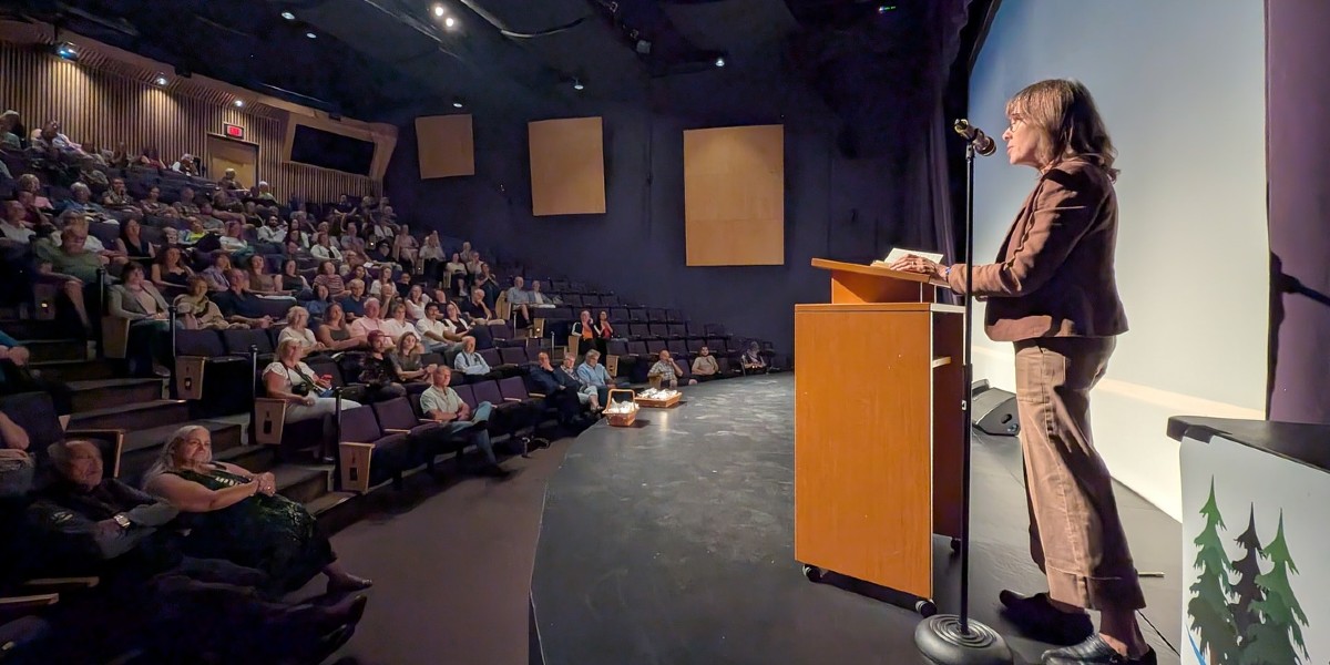 Sonia Furstenau stands on stage behind a podium in front of a theatre of people at the film screening for the documentary film, "Trouble In the Headwaters."